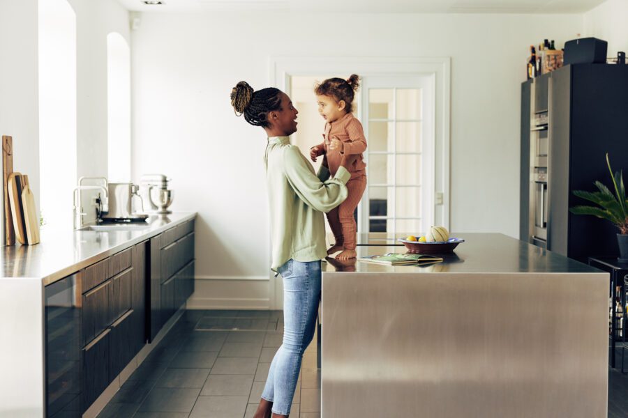 Smiling young African mom and her cute little daughter standing in their kitchen after reading a storybook Smiling mom standing with her cute little girl in their kitchen adorable, adult, affection, african, african american, biracial, black, book, care, cheerful, child, childhood, children, counter, cute, daughter, domestic, family, fun, happiness, happy, home, joy, kitchen, laughing, little, love, loving, mom, mother, motherhood, parent, parenthood, parenting, people, playing, reading, rwandan, single mom, single mother, single parent, small, smile, smiling, story, toddler, together, woman, young